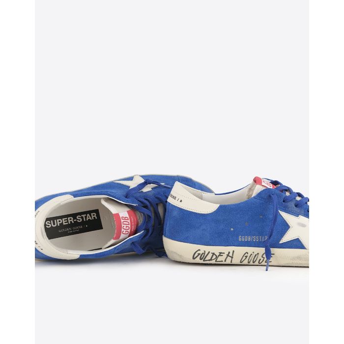 Sneakers Superstar Golden Goose homme en cuir suédé bleu, étoile blanche, arrière en cuir blanc. Détail de l'écriture effet graffiti "Golden Goose" sur la semelle.