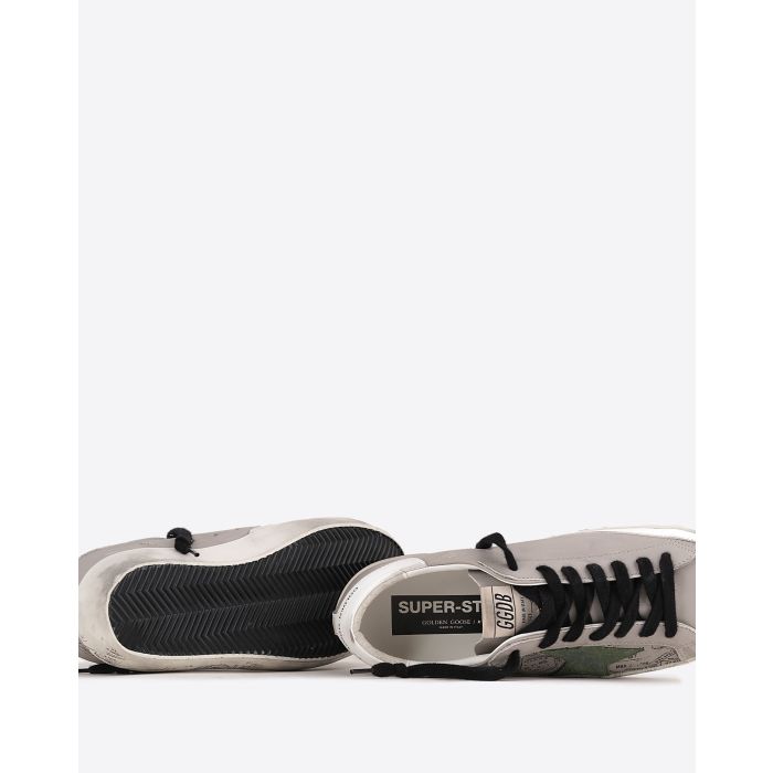 Sneakers Super-Star Golden Goose Homme en cuir taupe avec graffitis noirs arrière blanc étoile en cuir vert et lacet noir. Détail dessous de la semelle.