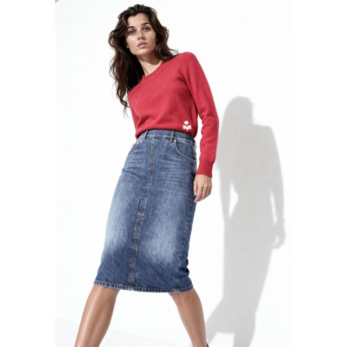 Jupe Kim droite longueur midi Haikure en denim bleu délavé, portée avec un pull rouge.