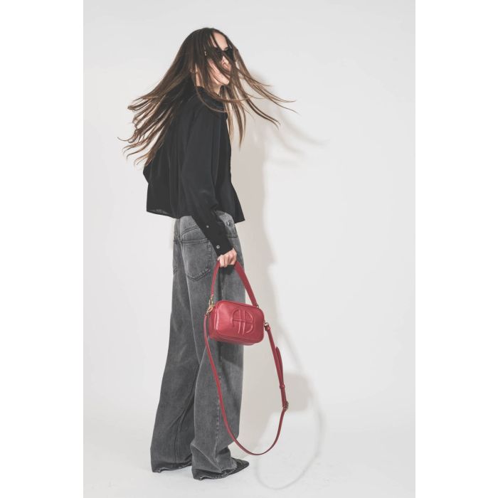 Chemise courte manches longue col Mao plis devant en viscose noire Adzara Marant Etoile. Portée de profil dos avec un jean large fluide gris clair Joanny Marant Etoile et des escarpins en cuir noir Slingbacks à talons Freya Anine Bing. Sac en cuir rouge l