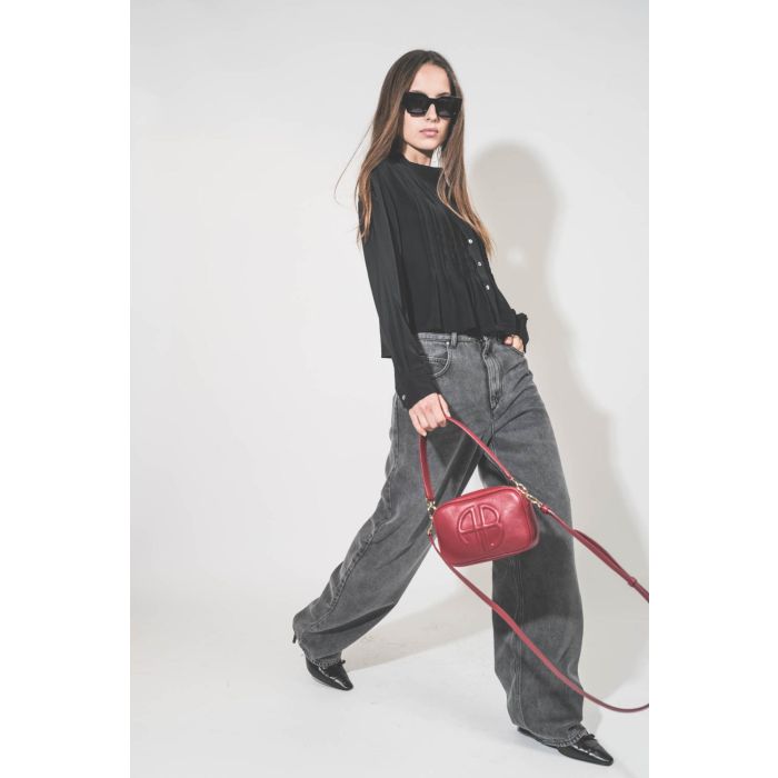 Chemise courte manches longue col Mao plis devant en viscose noire Adzara Marant Etoile. Portée de profil avec un jean large fluide gris clair Joanny Marant Etoile et des escarpins en cuir noir Slingbacks à talons Freya Anine Bing. Sac en cuir rouge logo 