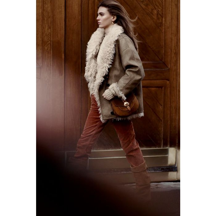 Manteau Clea Isabel Marant Etoile en faux mouton retourné taupe. Porté de profil avec un jean slim en velours côtelé. 