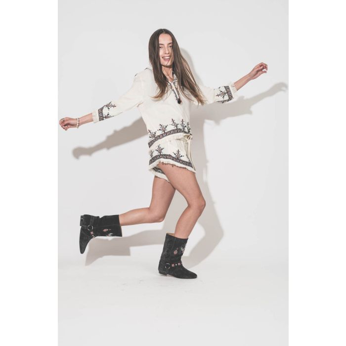 Short court écru brodé taille élastique avec cordon écru Kriss Marant Etoile. Porté de profil avec un top coordonné Kameya Marant Etoile et des boots en cuir suédé noir délavé brodé Siani Isabel Marant. Bijoux Isabel Marant.