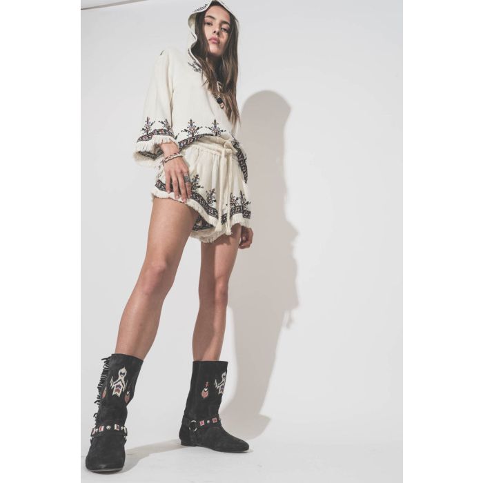 Short court écru brodé taille élastique avec cordon écru Kriss Marant Etoile. Porté de profil avec un top coordonné Kameya Marant Etoile et des boots en cuir suédé noir délavé brodé Siani Isabel Marant. 