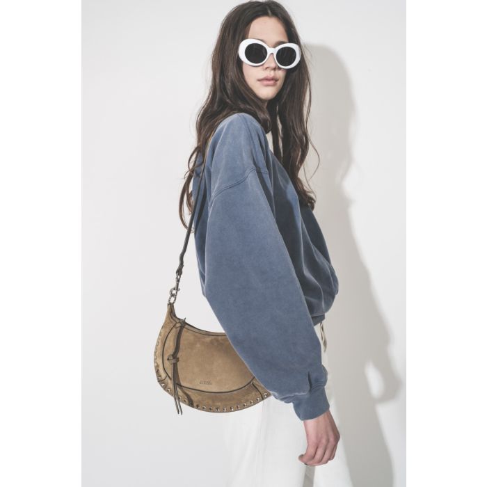 Sweatshirt Sauria Isabel Marant Étoile en coton bleu indigo, porté de profil avec un sac Isabel Marant.