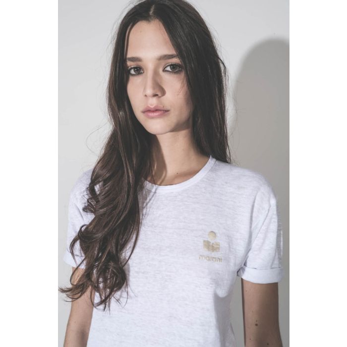 T-shirt Koldia Isabel Marant Étoile en lin blanc, logo or au-dessus de la poitrine, porté de face. Détail du mini-logo doré.