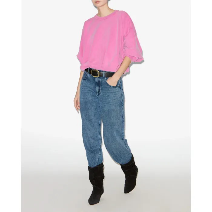 Jean fluide Jenny Isabel Marant en denim bleu clair. Vue de face. Forme classique « Regular ». Porté avec un sweatshirt rose.