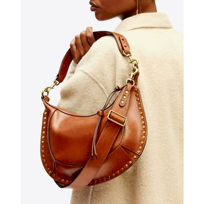 Sac Naoko Isabel Marant en cuir lisse cognac, porté à la main avec la anse courte. 