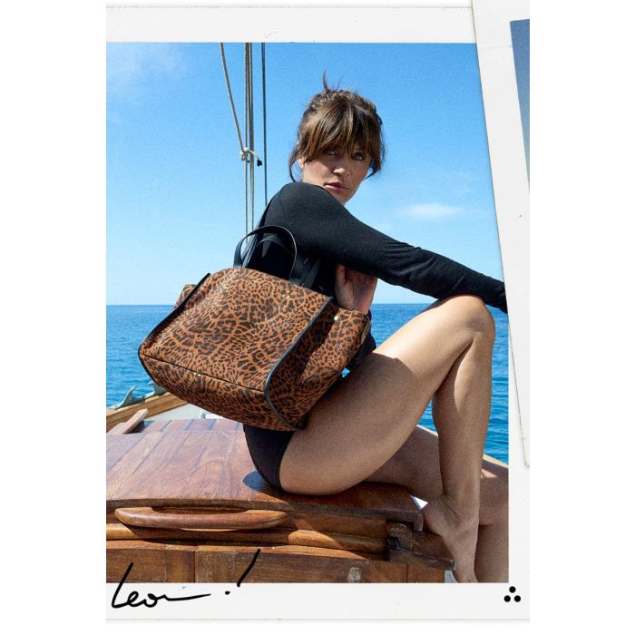 Sac cabas Léon M Jérôme Dreyfuss en cuir suédé imprimé à motif de chat sauvage, porté à l'épaule par Helena Christensen et photographié par Germain Chauveau à Ibiza.