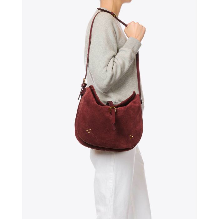 Sac besace Luis Jérôme Dreyfuss en cuir suédé brulé, porté de profil à l'épaule bandoulière longue.