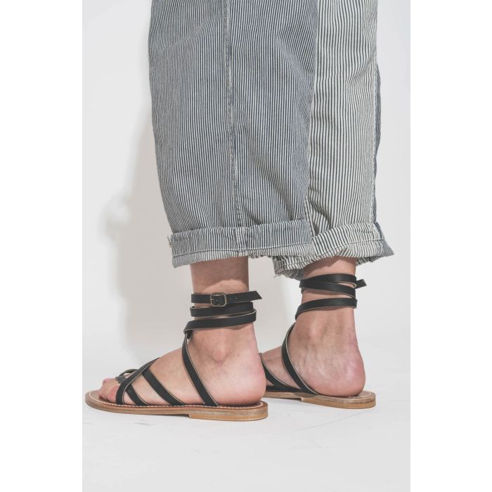 Sandales plates en cuir noir Zenobie K.Jacques Saint-Tropez. Porté de dos avec un pantalon à rayures Cargo Railroad R13 denim.