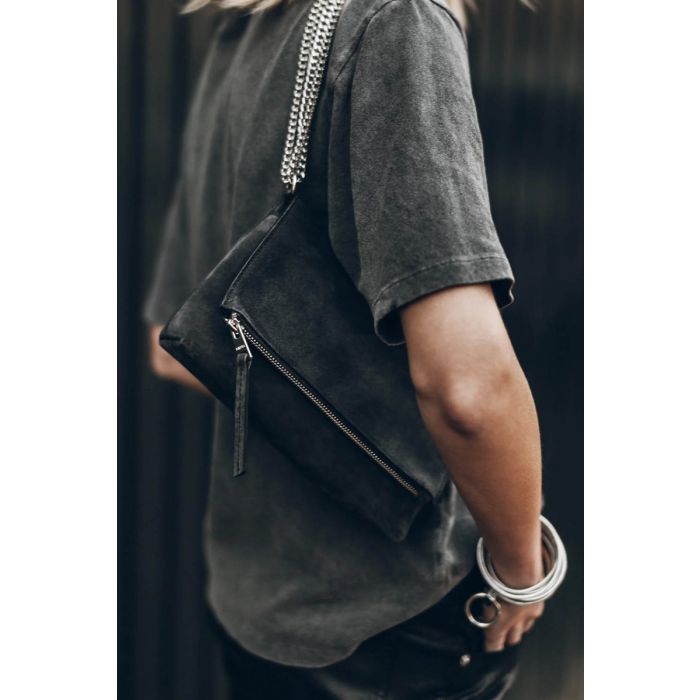 Sac Zowie Mikuta en cuir suédé noir et chaine en métal argenté, porté à l'épaule.