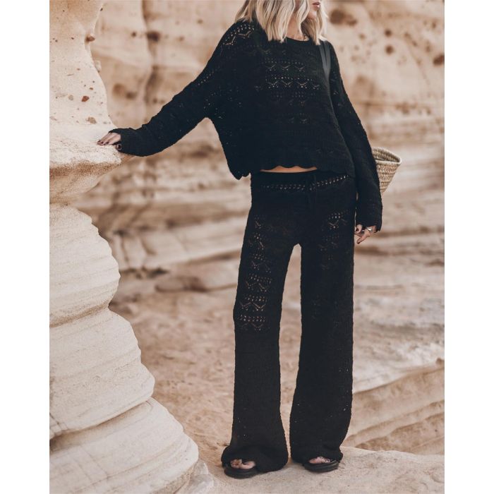Pantalon taille basse en crochet noir en lin et coton Mikuta. Porté de face avec un pull assorti.