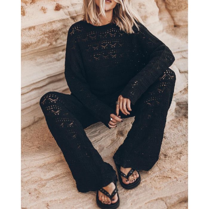 Pantalon en crochet noir en lin et coton Mikuta. Porté avec un pull noir en crochet assorti et des sandales noires.