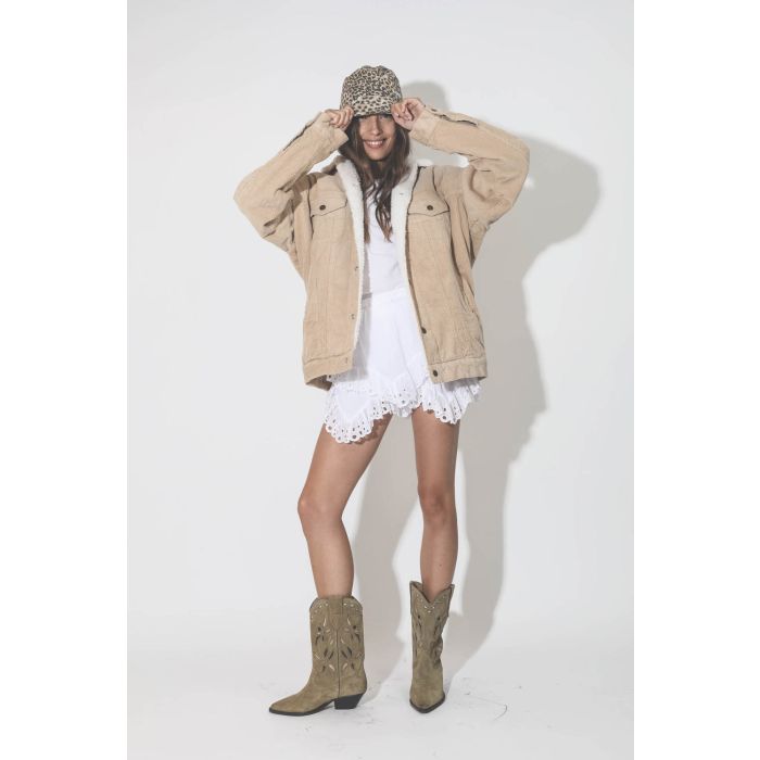 Veste en velours côtelée beige doublé de fausse fourrure Trucker Serena Denimist. Porté avec une mini-jupe short en dentelle blanche.