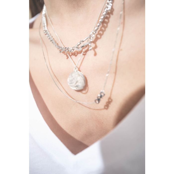Collier en argent chaine avec une médaille en argent gravée "GB.03" et pavée de diamants et une médaille en cristal de roche gravée "AMOUR" Pascale Monvoisin. Porté en accumulation avec un collier chaine en argent Berline Maria Black et un collier chaine 