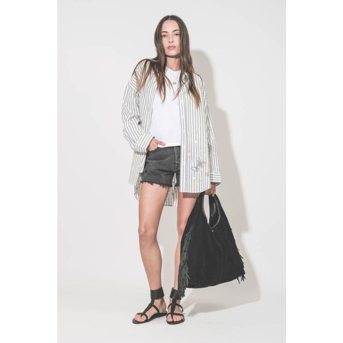 Chemise oversized en popeline blanche à rayures noires et graffiti Drop Neck R13. Portée ouverte de face sur un tee-shirt blanc The Great avec un short en jean noir Mikuta, des sandales Caravelle K.Jacques St Tropez et un sac à franges Paco Jérôme Dreyfus