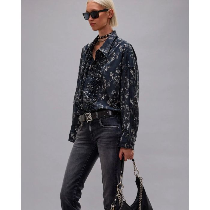 Chemise oversize à jabots R13 en voile de coton noir imprimé floral, portée de profil rentrée dans un jean noir.