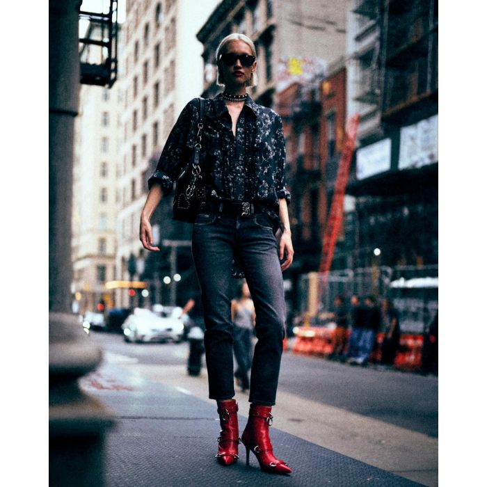 Jean slim raccourcie Boy Straight R13 en denim noir délavé Essex Black Stretch, porté de face avec une chemise à jabots imprimé floral noire.