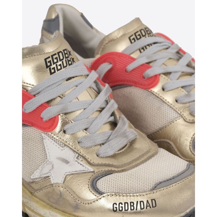 Sneakers Running Dad Golden Goose homme dorées étoile blanche. Détail des passages de lacets rouges. 