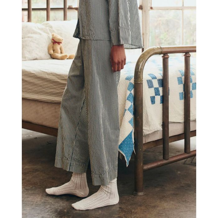 Pantalon Easy Sleep The Great en coton rayé noir et crème, porté de profil.