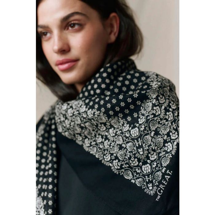 Grand foulard Bandana The Great en coton noir délavé, porté noué autour du cou.