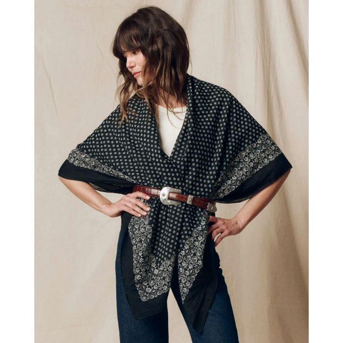 Grand foulard Bandana The Great en coton noir délavé, porté sur les épaules en triangle et ceinturé à la taille.