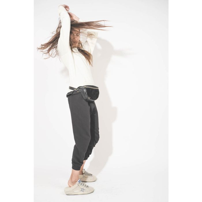 Pantalon de jogging taille basse à nouer sur les hanches resserré en bas bord côte noir The Cropped Sweatpant The Great. Porté avec un sweat-shirt Shrunken écru The Great et des sneakers Super Star sabot en fourrure écru 10757 Golden Goose. Sac lino banan