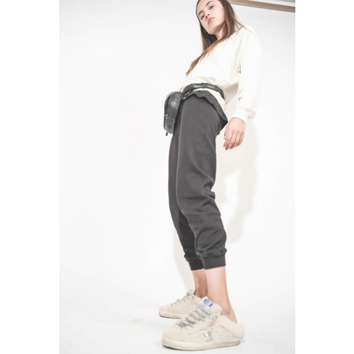Pantalon de jogging taille basse à nouer sur les hanches resserré en bas bord côte noir The Cropped Sweatpant The Great. Porté avec un sweat-shirt manches longues Shrunken écru The Great et des sneakers Super Star sabot en fourrure écru 10757 Golden Goose