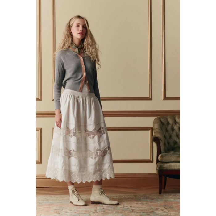 Jupe longue Rosette Crochet The Great en coton et dentelle blanche, portée de face avec un gilet.