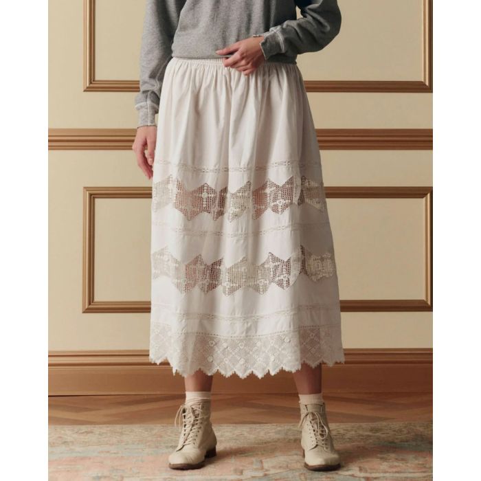 Jupe longue Rosette Crochet The Great en coton et dentelle blanche, portée de face avec un sweat-shirt gris chiné.