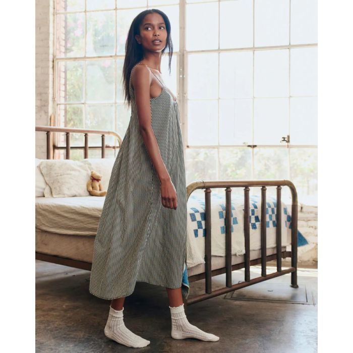 Robe longue à fines bretelles Slip Sleep The Great en coton rayé noir et crème, portée de profil.