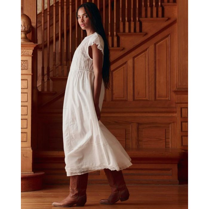 Robe longue Sonnet The Great en coton blanc et dentelle, portée de profil.