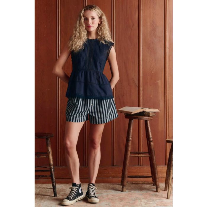 Top sans manches Sonnet The Great en coton et dentelle bleu marine, porté de face avec un short à rayures.