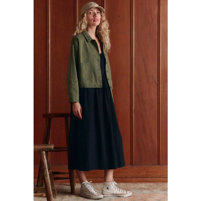 Veste de travail vintage Rancher The Great en coton kaki, portée de profil avec une robe longue noire.