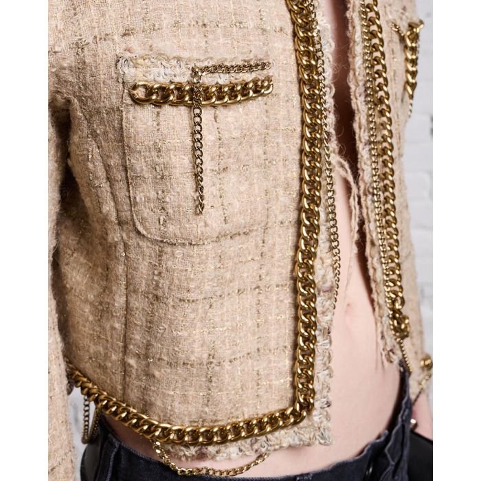 Veste courte en tweed beige avec détails de chaines R13. Détails de matière et chaines dorées.