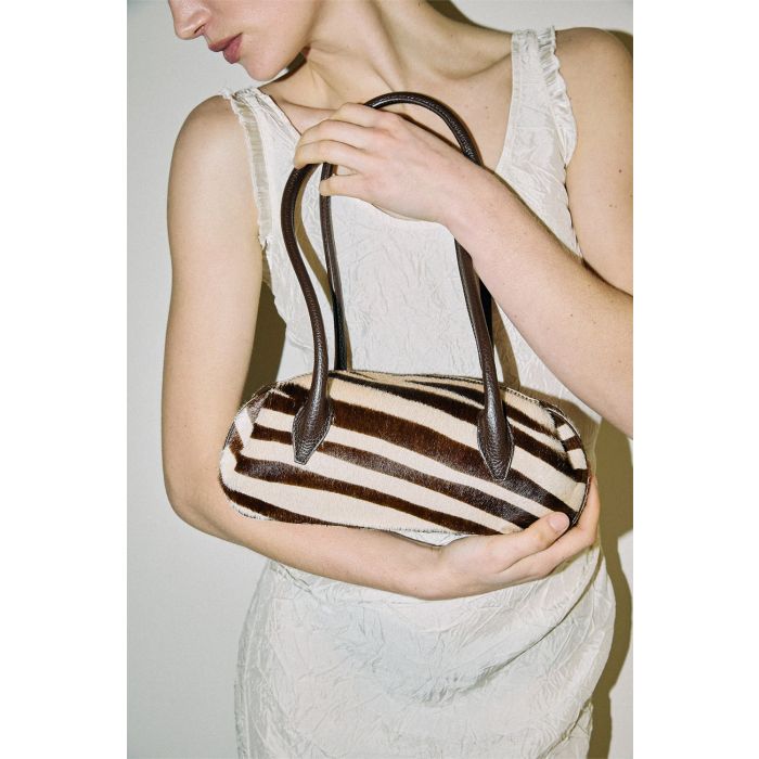Sac Mini Oyster Yuzefi en cuir pony Savanna imprimé zèbre marron et écru, mini sac baguette porté épaule au design contemporain. Porté dans les bras.