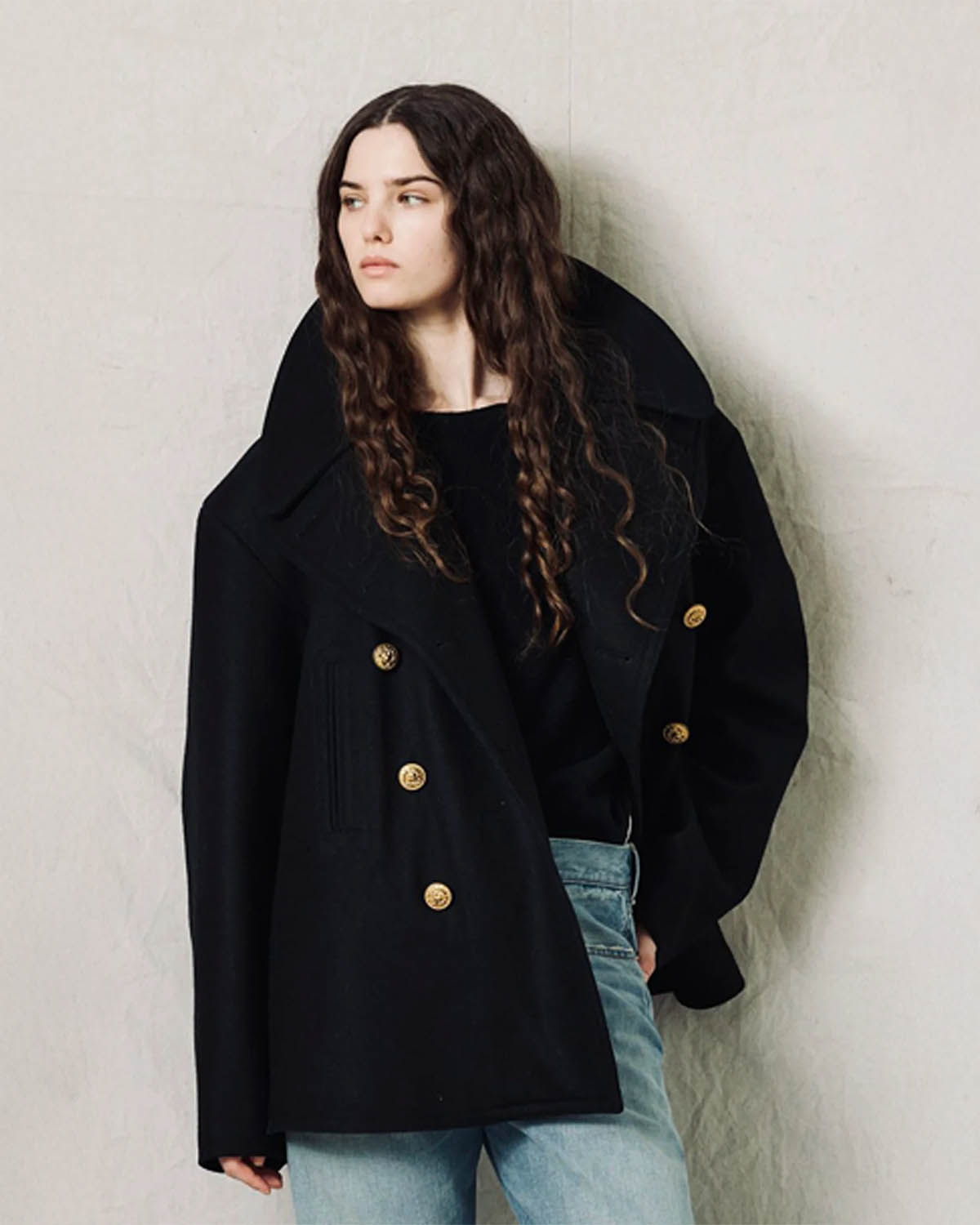 Caban oversize en drap de laine noir boutons gravés dorés Denimist. Porté ouvert col relevé.
