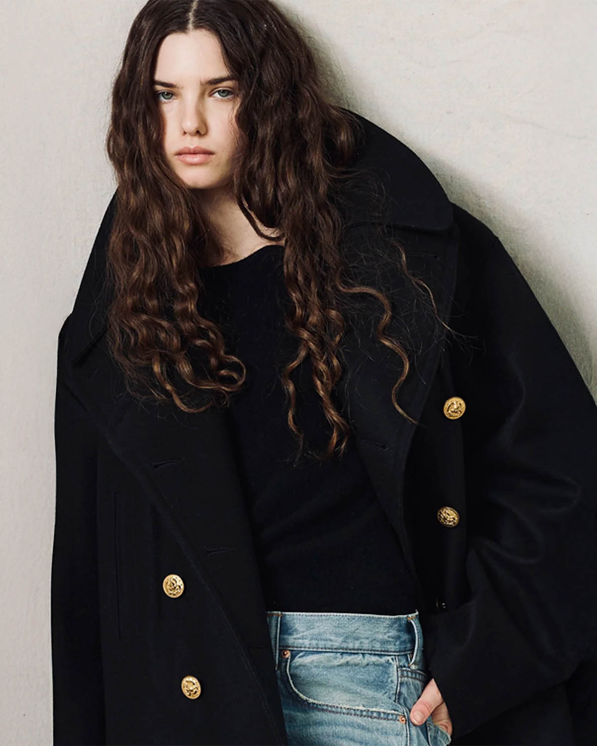 Caban oversize en drap de laine noir boutons gravés dorés Denimist. Porté avec un pull noir.