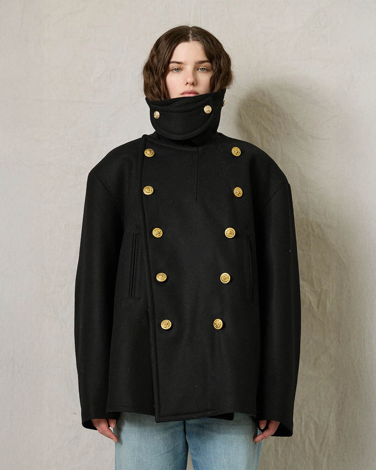 Caban oversize en drap de laine noir boutons gravés dorés Denimist. Porté col relevé et fermé par une patte de boutonnage amovible. 