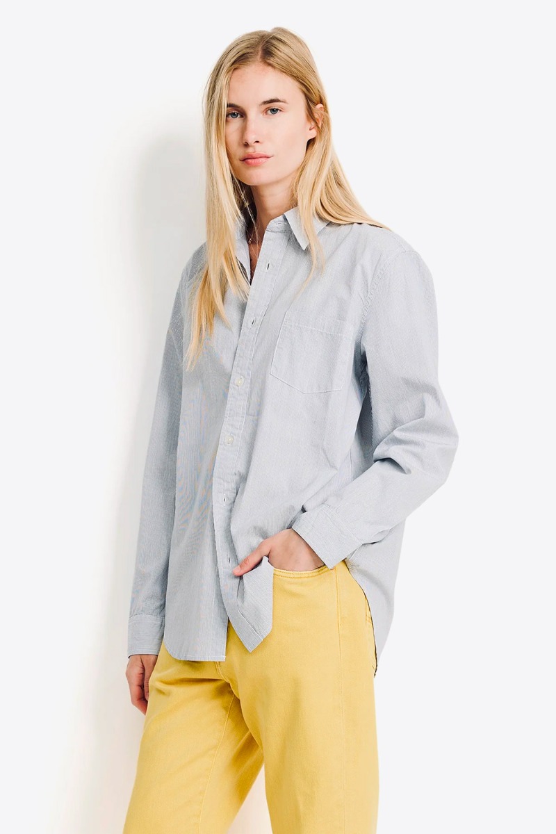 Chemise Boyfriend Denimist en coton &agrave; fines rayures &eacute;cru et marine, port&eacute;e de profil avec un jean droit.