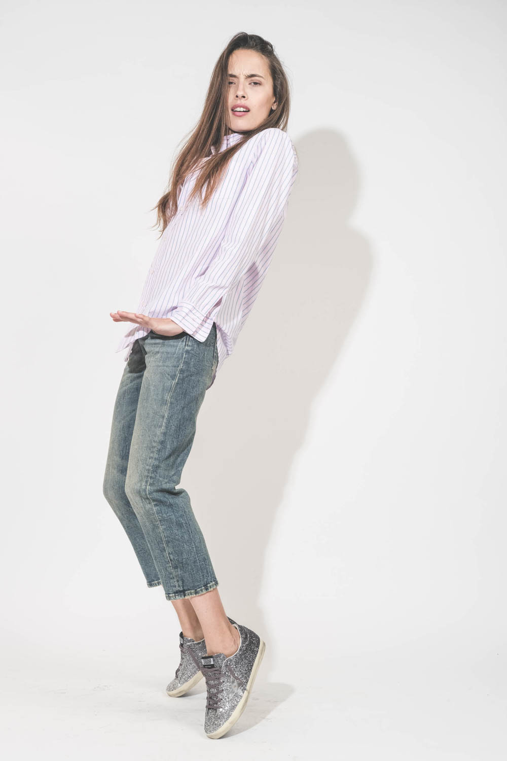 Chemise en popeline de coton rayé rose-bleu-blanc Boyfriend Denimist. Portée de profil avec un jean Boy Straight bleu R13 denim et des sneakers en cuir à paillettes Super-Star Golden Goose. 