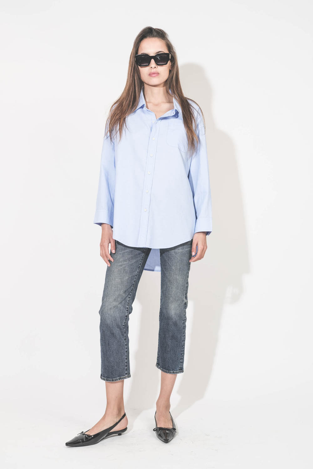 Produit Chemise oxford classique plus longue derrière que devant Button Front bleu ciel Denimist. Porté de face avec un jean Boy Straight Mire Blue Stretch R13 et des ballerines en cuir noir vernis Slingback Hells Zoey Anine Bing. Lunettes de soleil montures noir