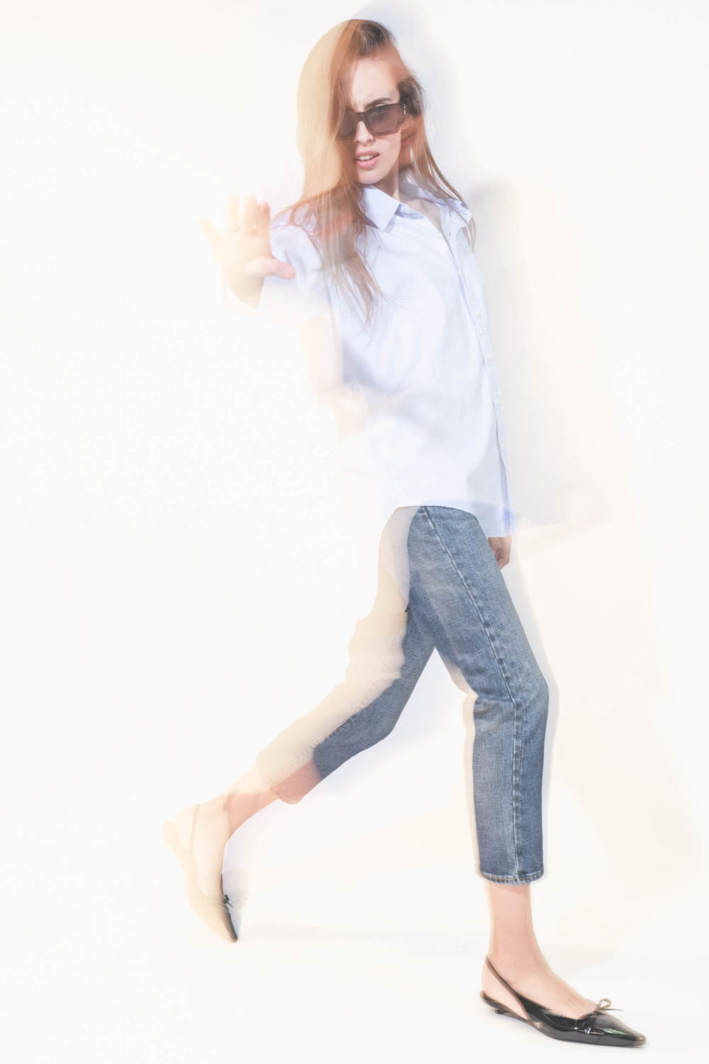 Chemise oxford classique plus longue derrière que devant Button Front bleu ciel Denimist. Porté de profil avec un jean Boy Straight Mire Blue Stretch R13 et des ballerines en cuir noir vernis Slingback Hells Zoey Anine Bing. Lunettes de soleil montures no