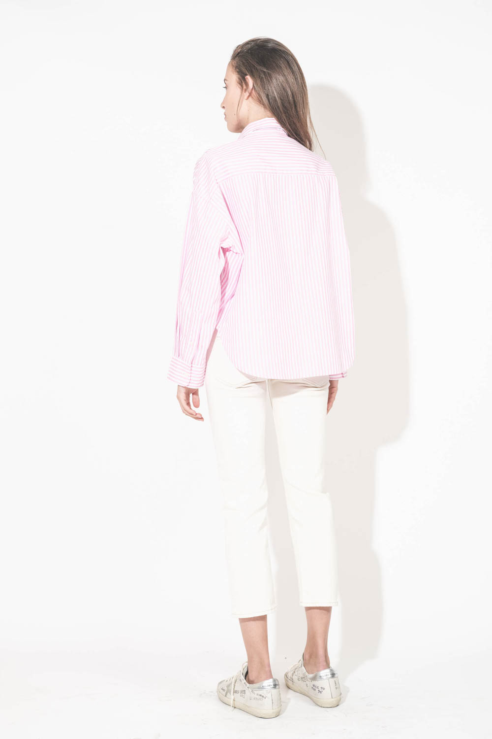 Chemise courte en popeline de coton rayée rose et blanche Cropped Shirt Denimist. Portée de dos avec un jean boy straight écru stretch R13 denim et des sneakers Super-Star en cuir blanc Graffiti Golden Goose. 