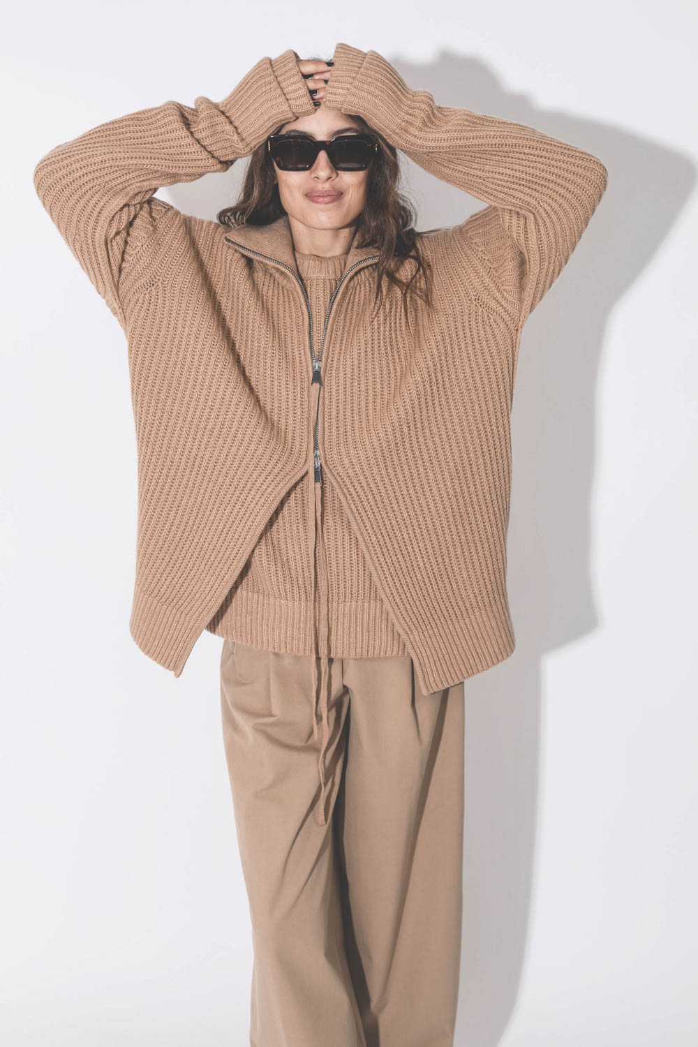 Gilet zip camionneur en maille cachemire camel Maison Flaneur. Porté avec des lunettes en écaille.