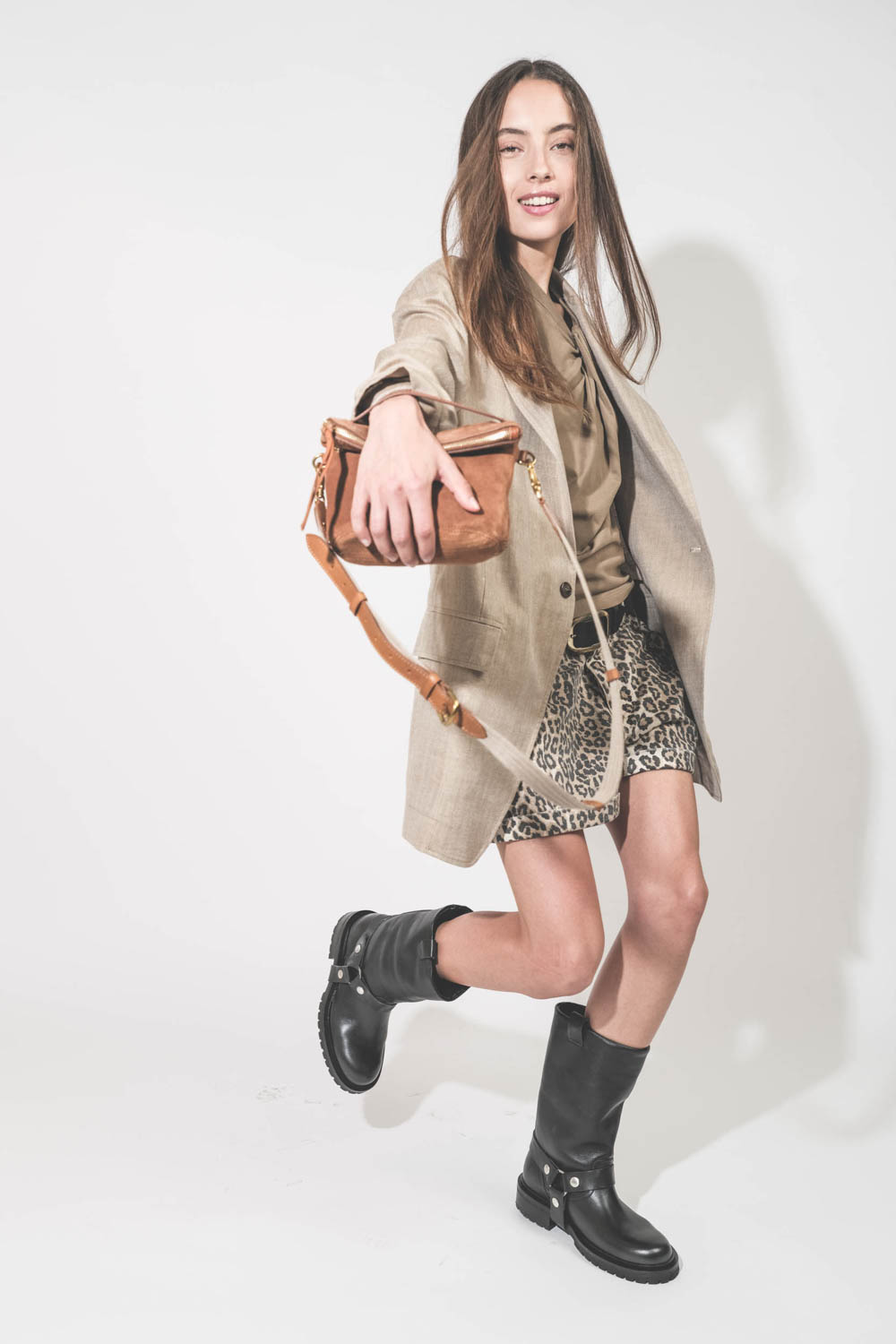 Bottes en cuir noir avec sangles amovibles Kurt Biker Golden Goose. Portées de profil avec une veste Ragged Oversized en lin beige R13 et un short Pocket en toile léopard R13. Ceinture en cuir noir Dara Isabel Marant et pochette en cuir suédé caramel Luck