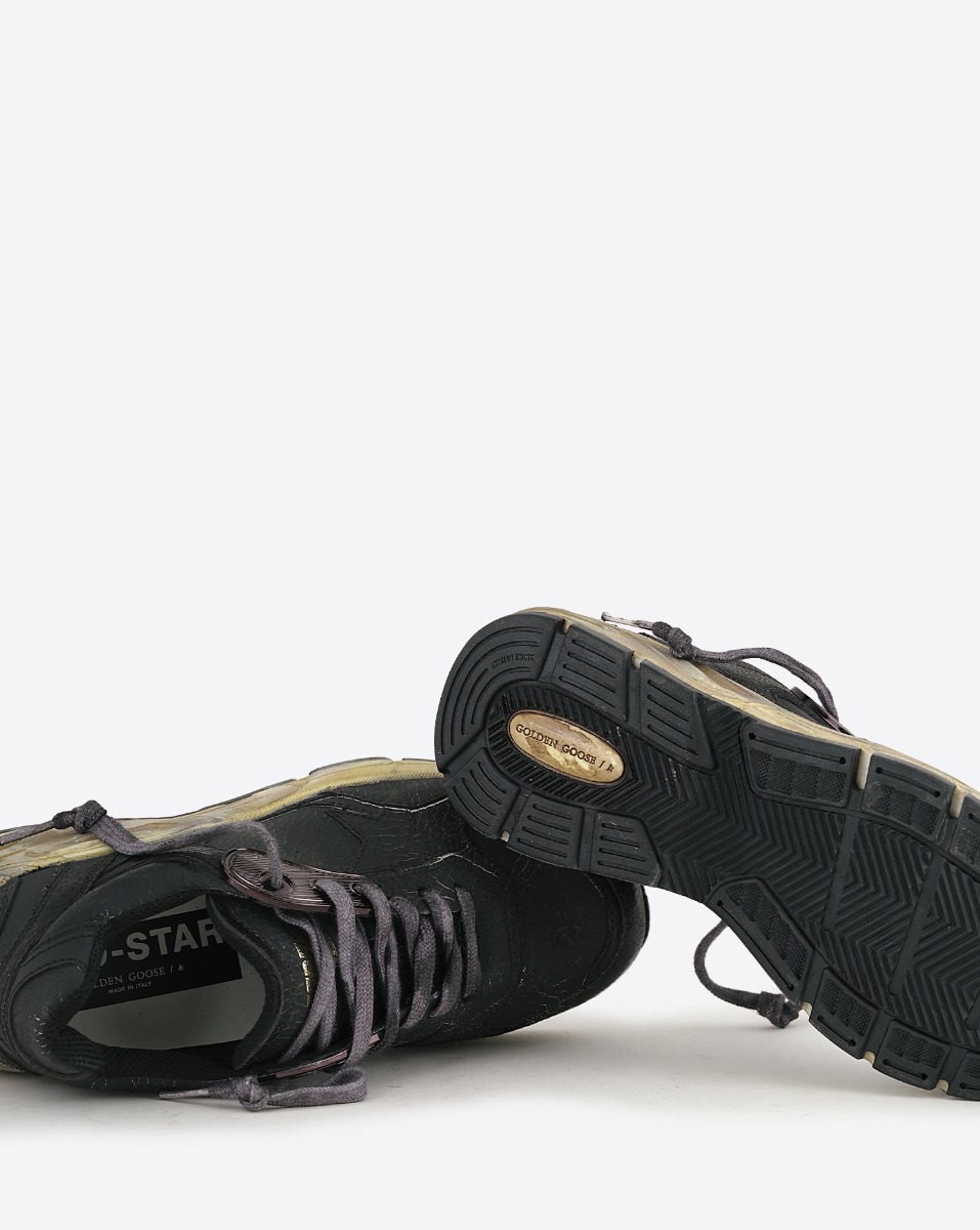 Sneakers Running Dad Golden Goose en cuir craquel&eacute; noir, &eacute;toile noire, semelle dor&eacute;e. D&eacute;tails des semelles.