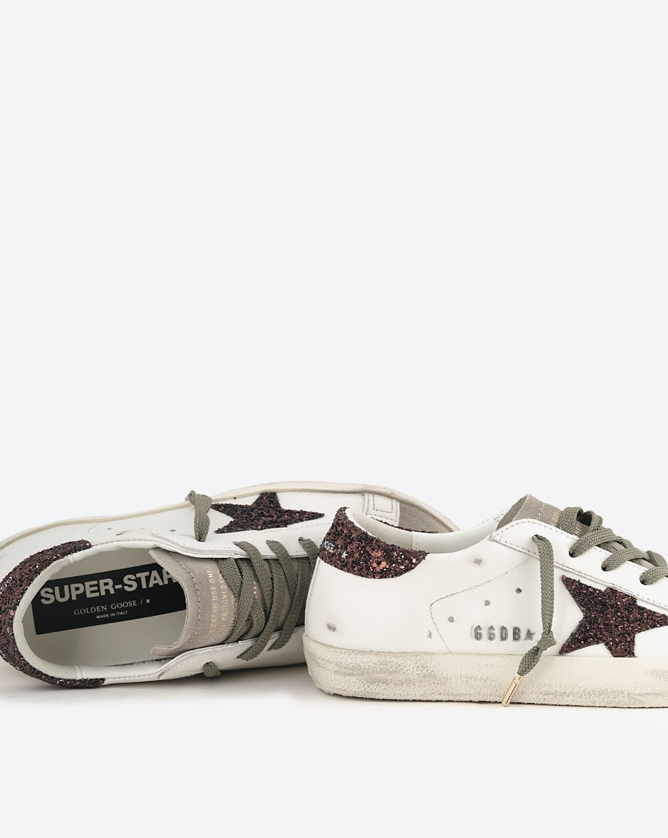 Sneakers Superstar Golden Goose femme en cuir blanc avec &eacute;toile et talon arri&egrave;re &agrave; paillettes marron. D&eacute;tail du logo GGDB en lettres m&eacute;talliques argent&eacute;es sur le c&ocirc;t&eacute;.
