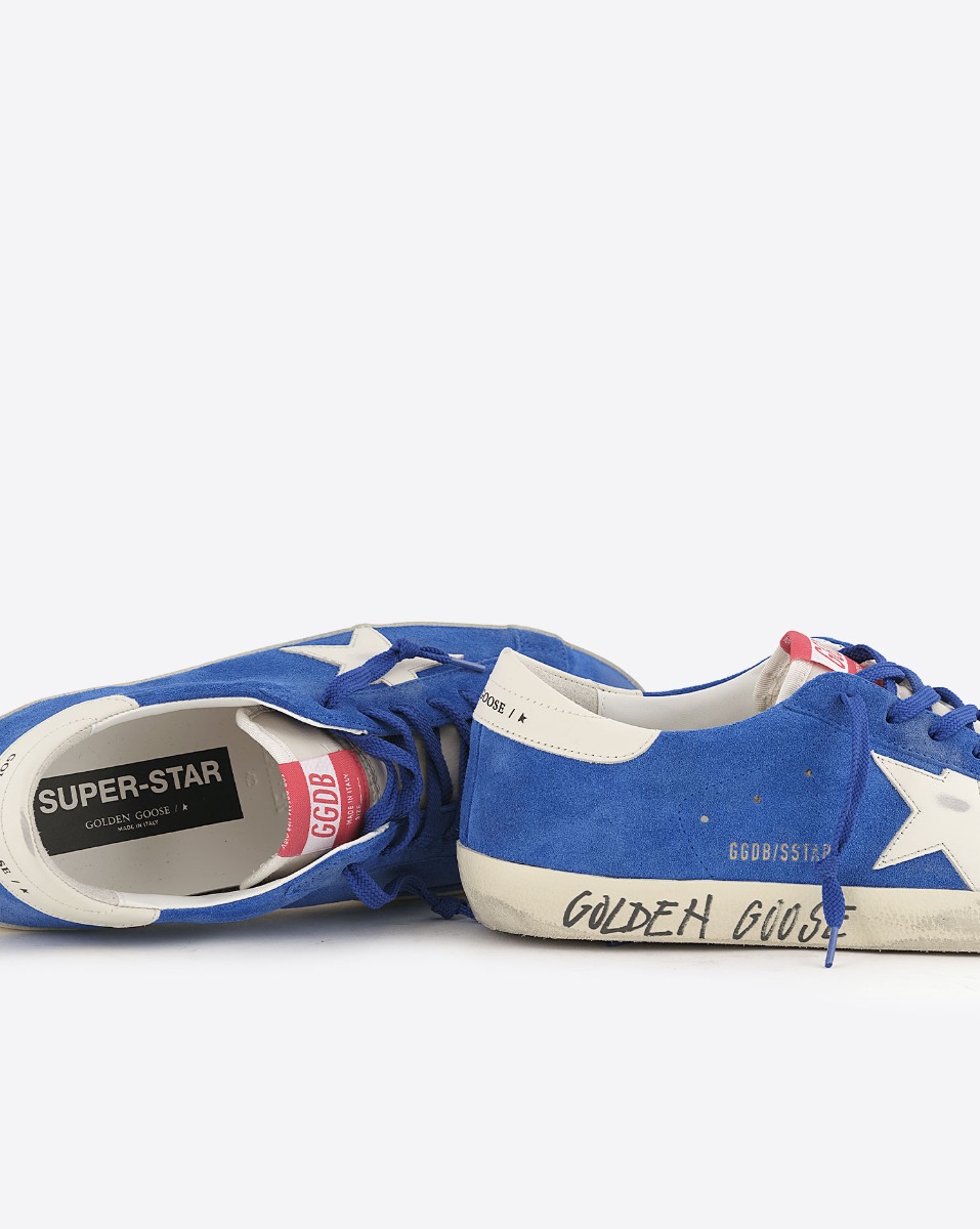 Sneakers Superstar Golden Goose homme en cuir su&eacute;d&eacute; bleu, &eacute;toile blanche, arri&egrave;re en cuir blanc. D&eacute;tail de l'&eacute;criture effet graffiti "Golden Goose" sur la semelle.